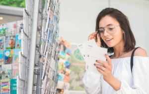  Junge Frau wählt eine Postkarte aus.