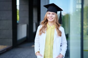 Junge Frau mit Diplomhut lächelt nach dem erfolgreichen Abschluss – Tipps für die perfekte Diplomarbeit schreiben lassen