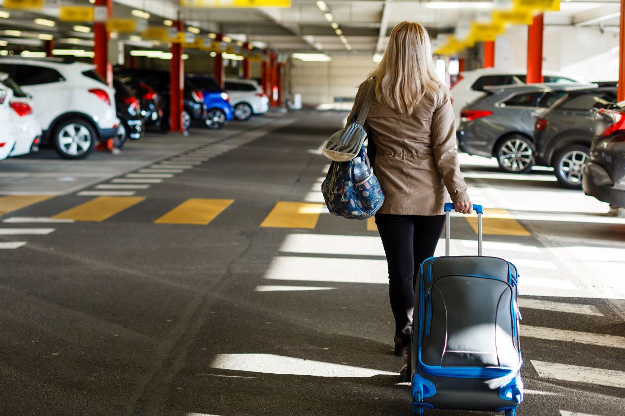 Reisende Frau mit Gepäck läuft durch ein überdachtes Parkhaus am Flughafen Nürnberg in Richtung Terminal.