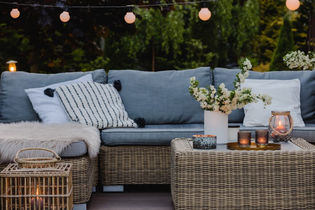 Elegante Outdoor-Lounge mit Rattanmöbeln, weichen Kissen und stimmungsvoller Beleuchtung für eine gemütliche Atmosphäre im Garten.