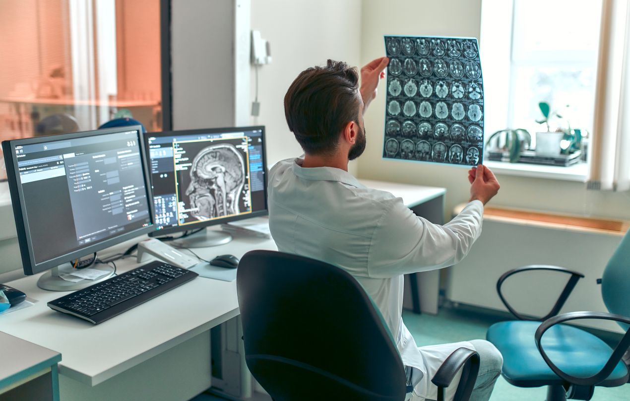 Arzt betrachtet MRT-Aufnahmen eines Gehirns in der Radiologie Köln. Moderne Bildgebung für exakte medizinische Diagnosen.